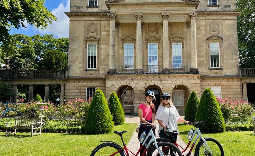 Two people with bikes in front of the Holburne Museum in Bath